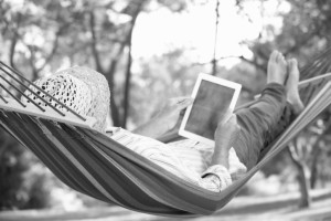 Person laying on a hammock, reading an eBook.